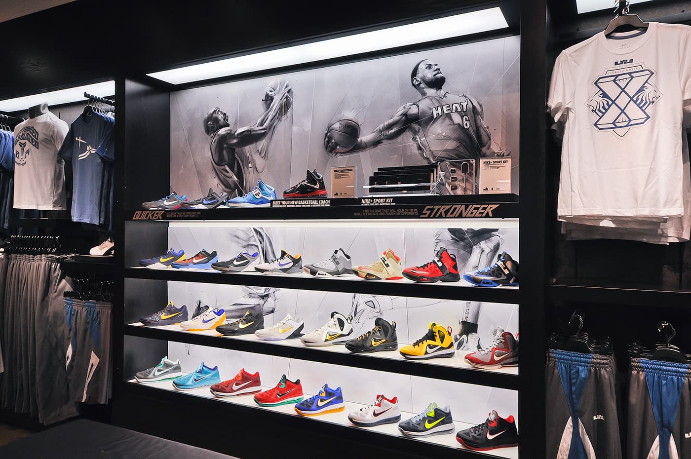 Nike House of Hoops retail footwear wall featuring illustrations of LeBron James and Kobe Bryant behind rows of basketball shoes, with apparel displays on either side.
