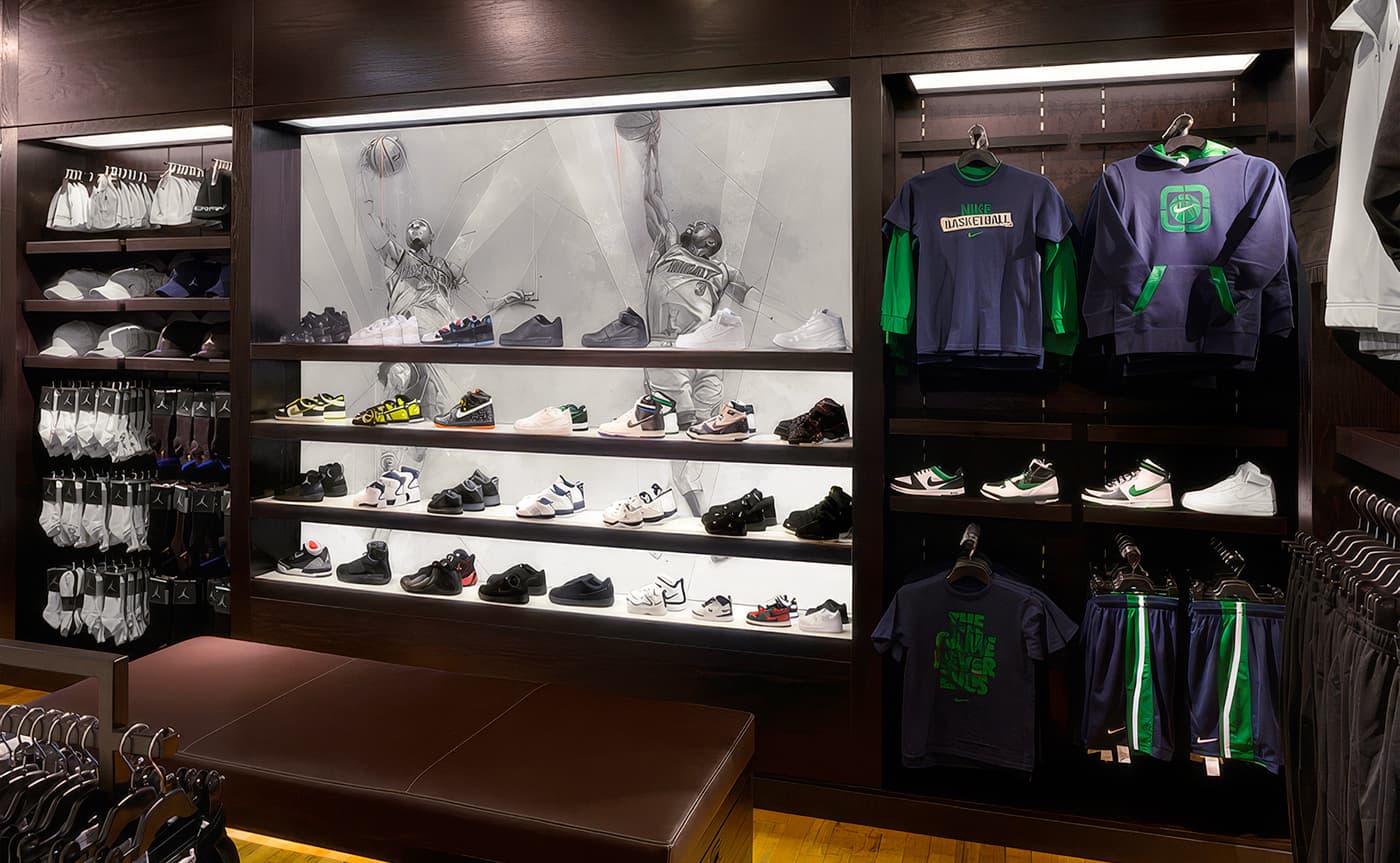 ike House of Hoops retail interior featuring monochromatic illustrations of NBA players behind illuminated basketball shoe displays, surrounded by Jordan Brand apparel and accessories.